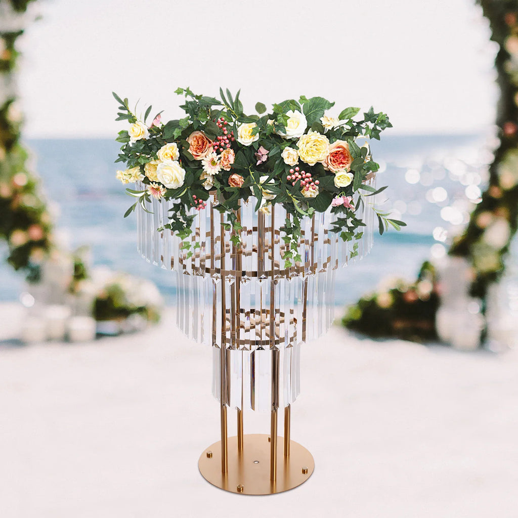 Three-tier gold metal wedding centerpiece stand with crystal drapes and a flower arrangement.