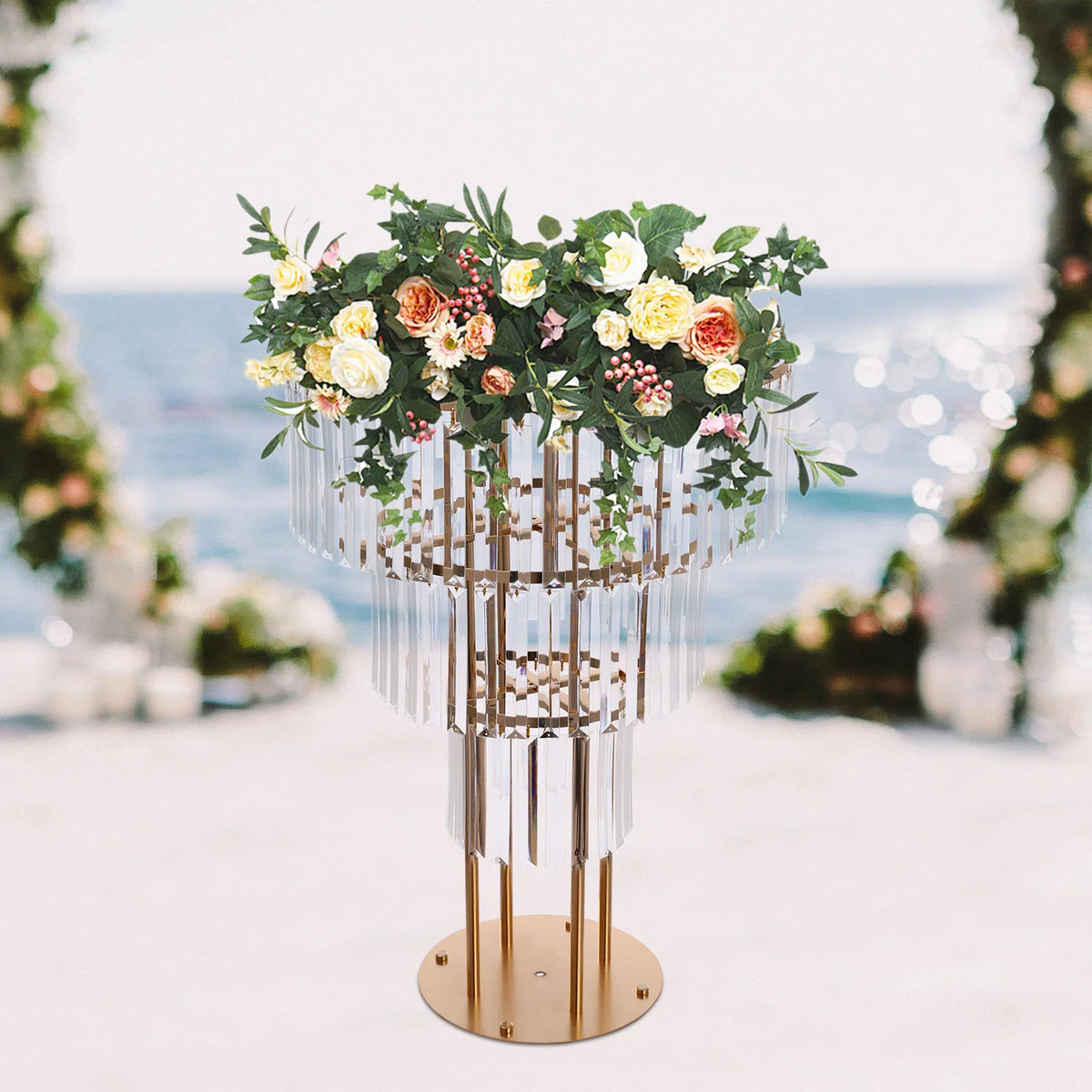 Three-tier gold metal wedding centerpiece stand with crystal drapes and a flower arrangement.