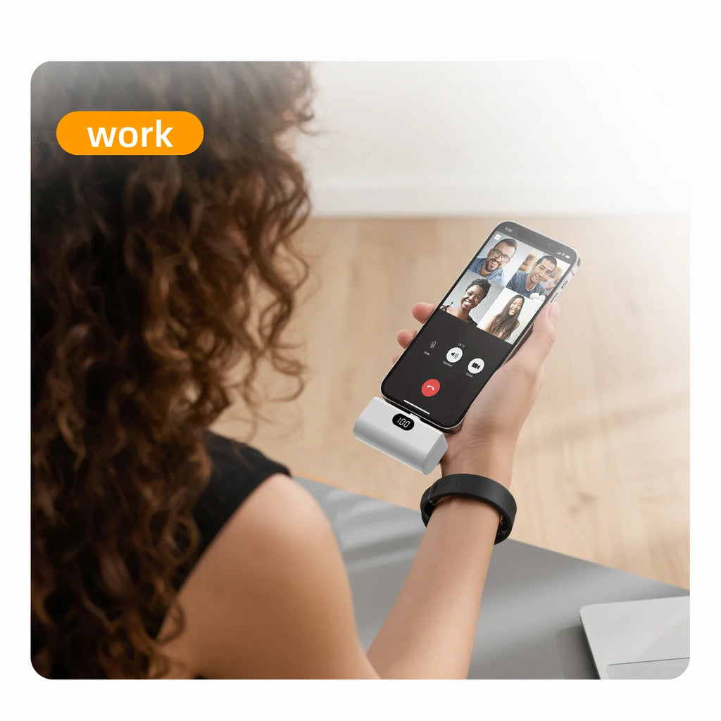 Person holding a smartphone connected to a compact portable battery pack during a video call