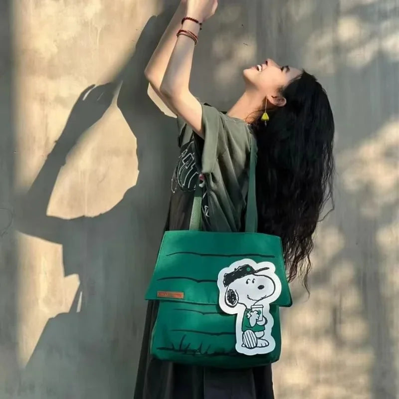 A woman wearing a green shoulder tote bag with a cartoon character design