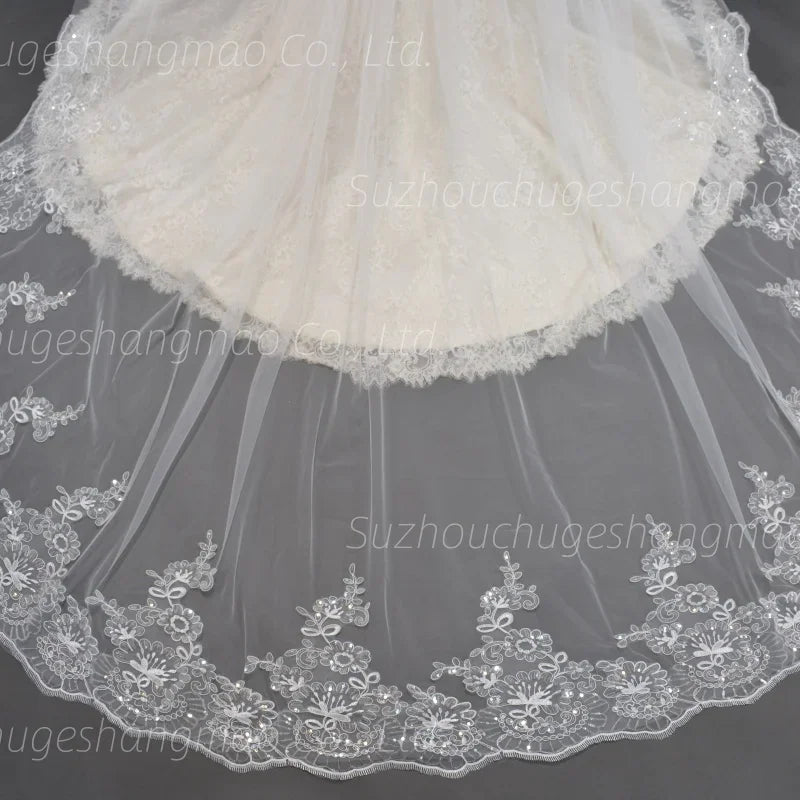 Close up of long wedding veil trim with intricate lace floral appliques and sequins