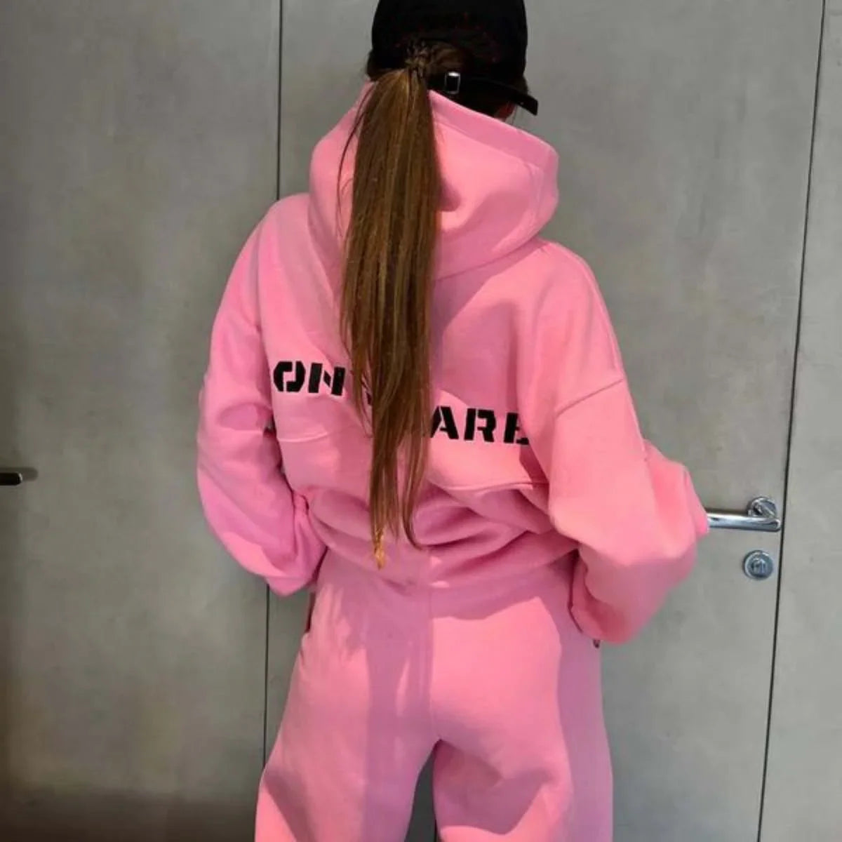 Woman wearing a pink hooded sweatshirt and matching sweatpants
