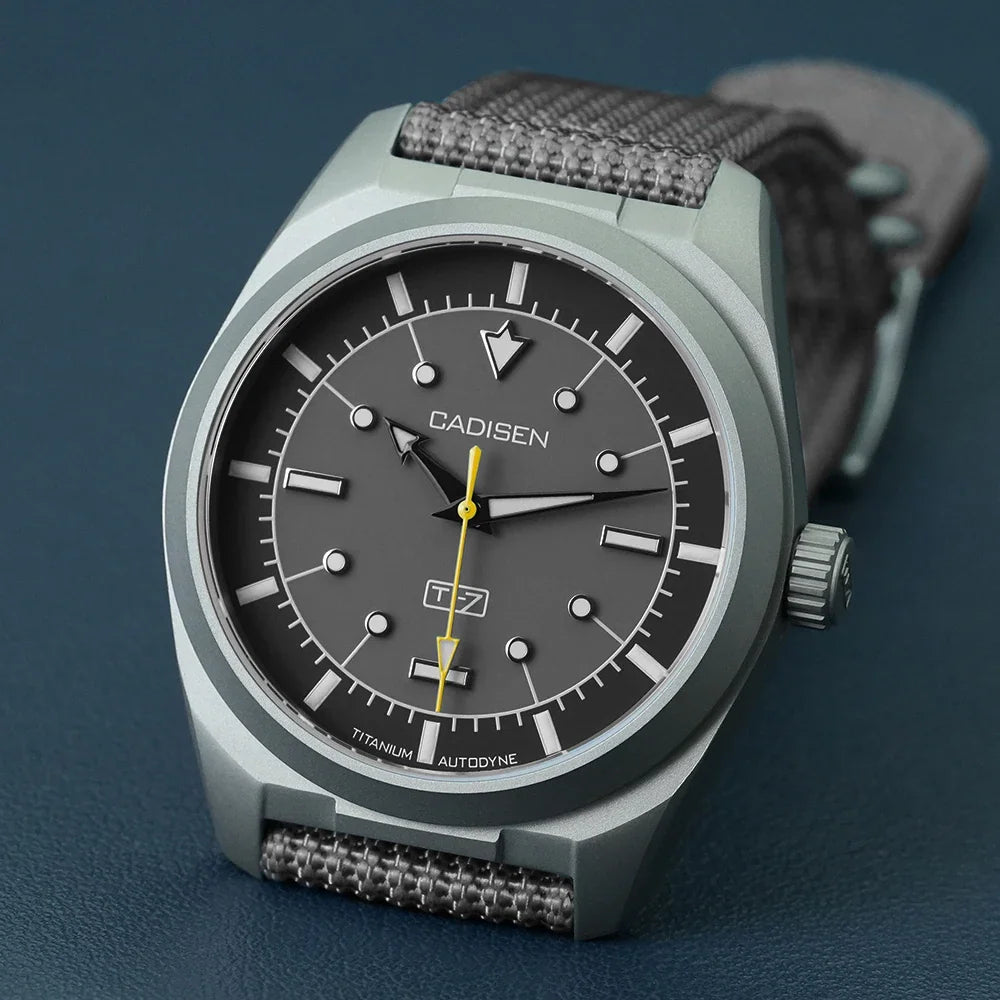 Grey titanium automatic watch with a grey canvas strap on a blue background