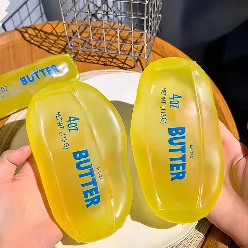 Hand holding two yellow butter stick shaped squishy fidget toys
