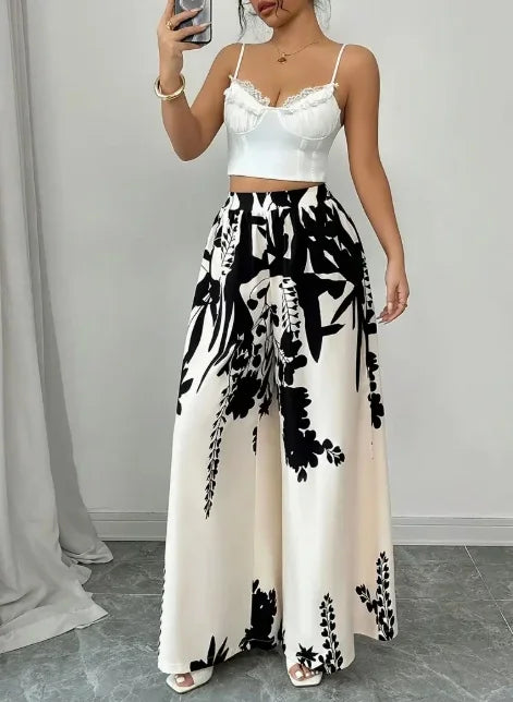 Woman wearing black and white floral print wide leg trousers with a white lace-trimmed crop top
