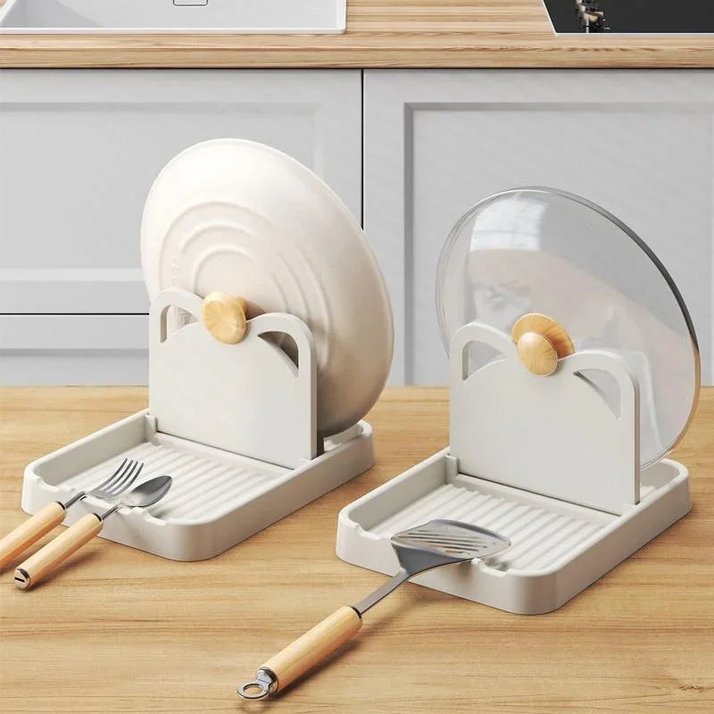 A beige kitchen utensil rest with a foldable stand for holding pan lids and spoons.