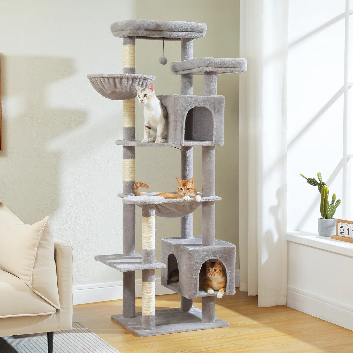 Large multi-level grey plush cat tree tower with scratching posts, perches, and condos with three cats.