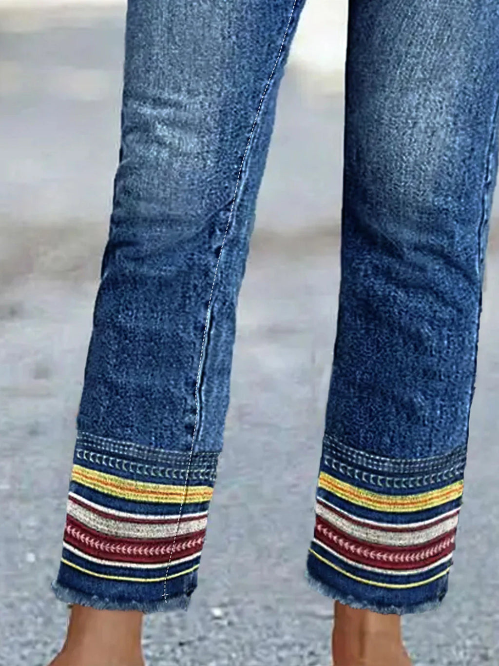Close up of denim jean cuffs with yellow white and red embroidered stripes