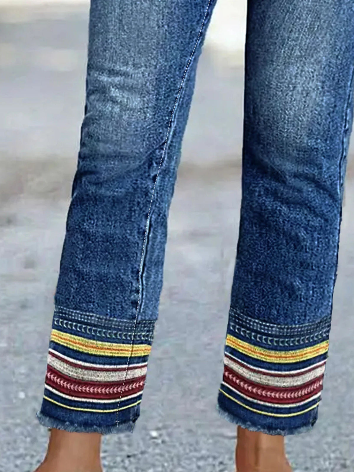 Close up of denim jean cuffs with yellow white and red embroidered stripes