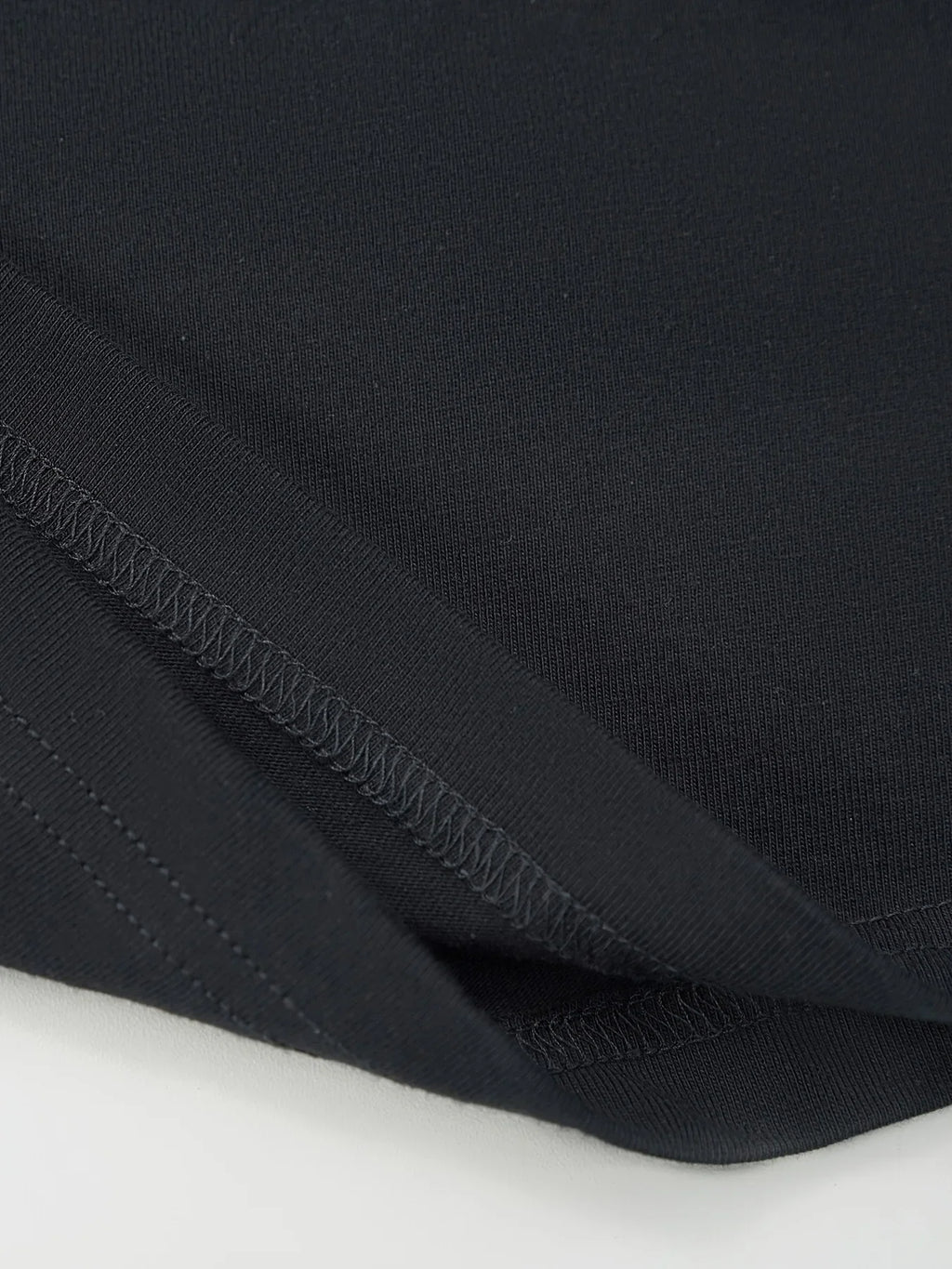 Close up of the fabric and hem of a black T-shirt