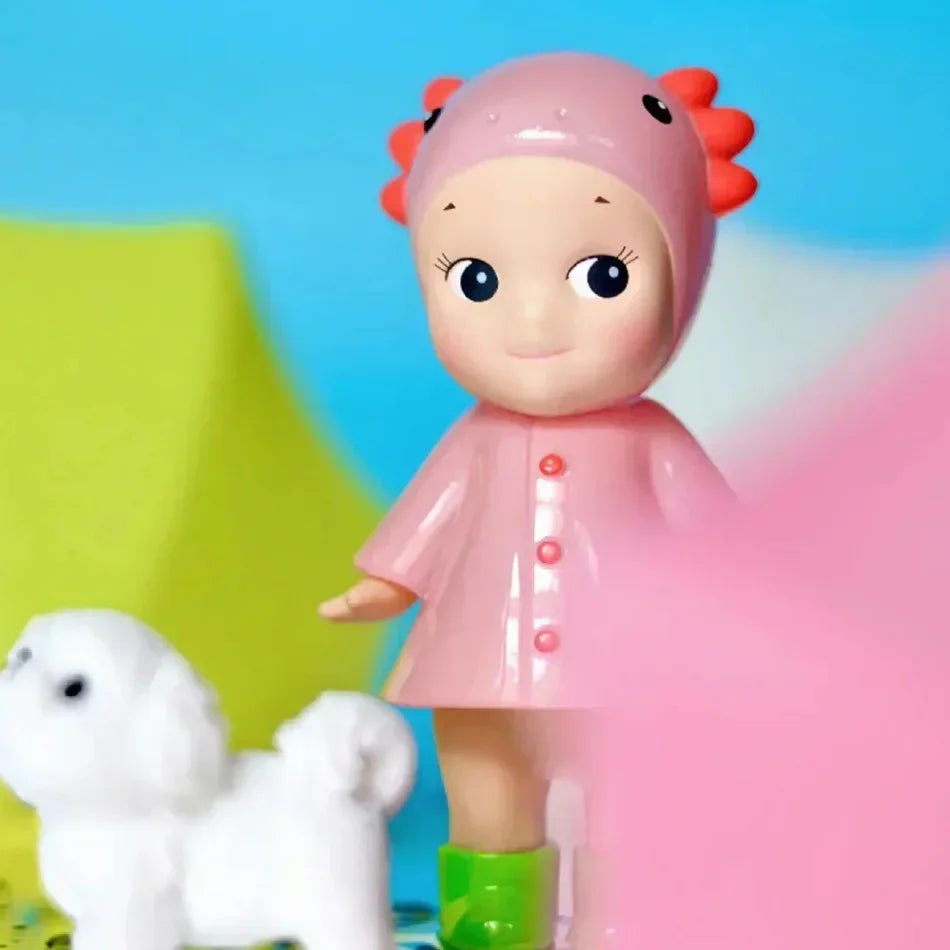 Small collectible doll figurine in a pink raincoat and hat with a toy dog