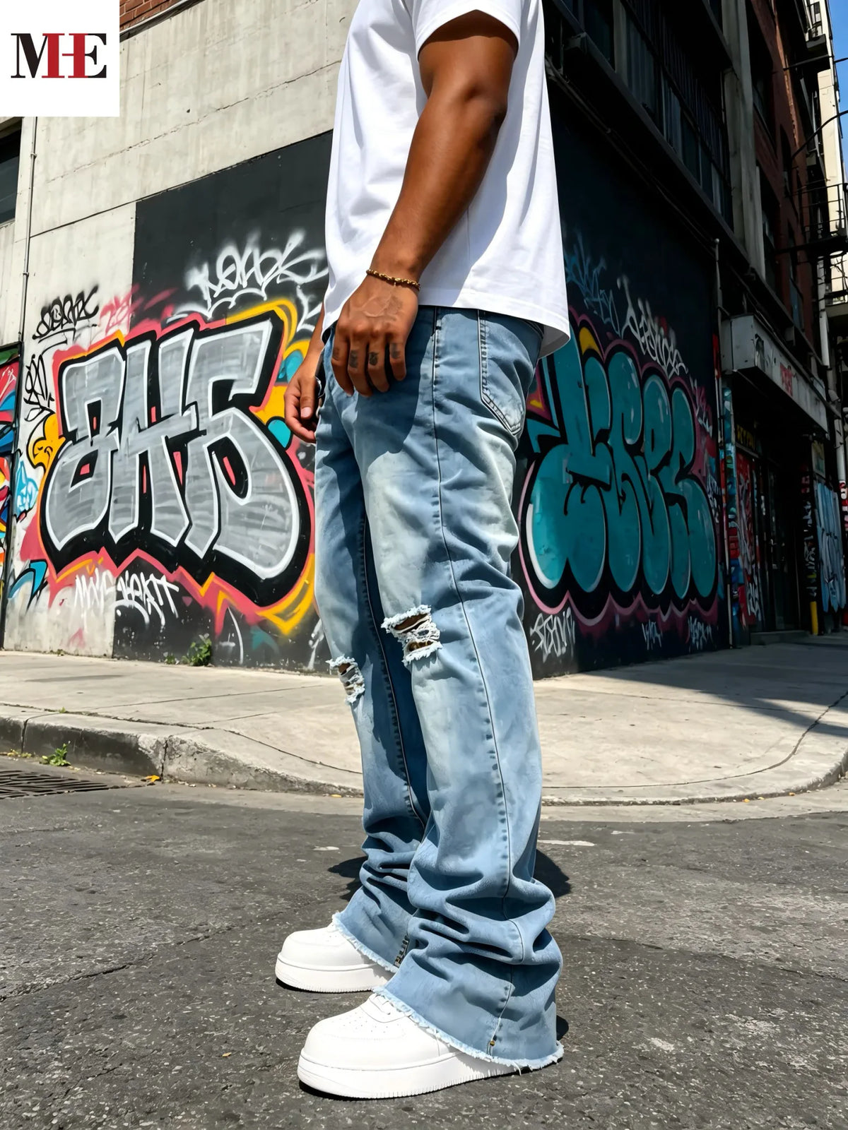 Side view of men's light blue distressed flared jeans with knee rips and frayed hem, worn with white t-shirt