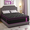 A thick hybrid mattress with a black and purple cover on a grey tufted bed frame.