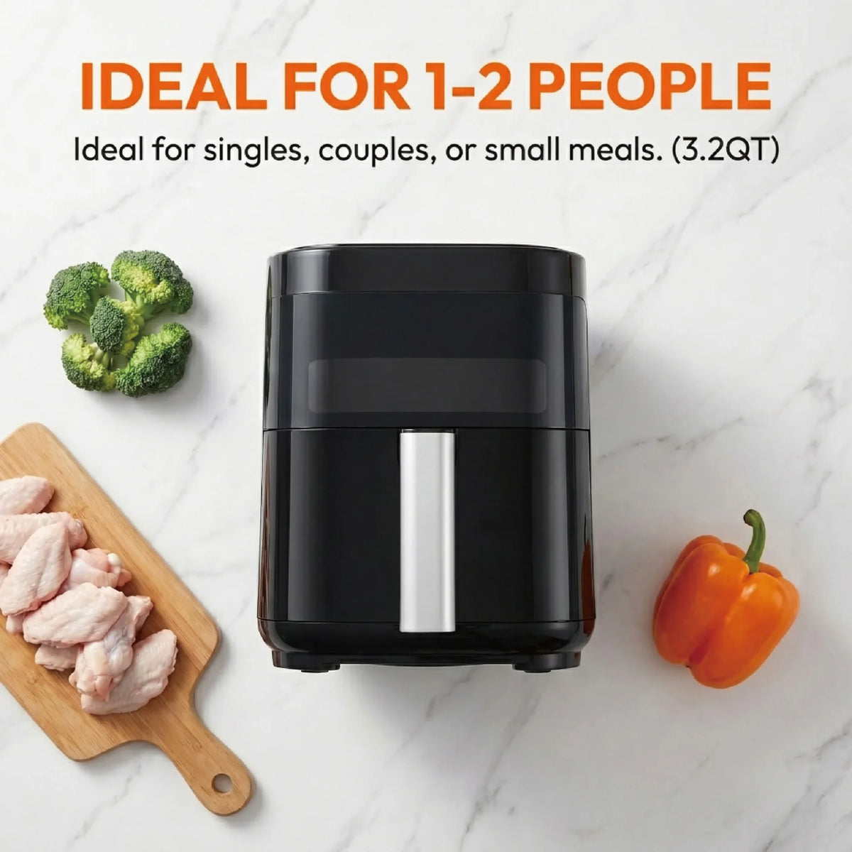 Small black air fryer with raw chicken, broccoli, and a bell pepper on a marble surface