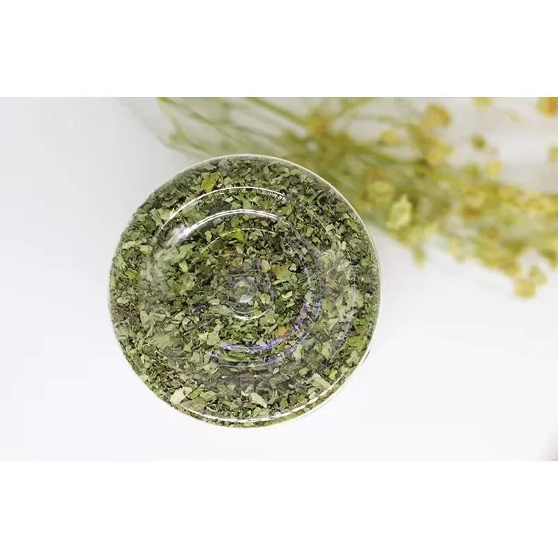 View through the bottom of a clear plastic jar containing dried green catnip