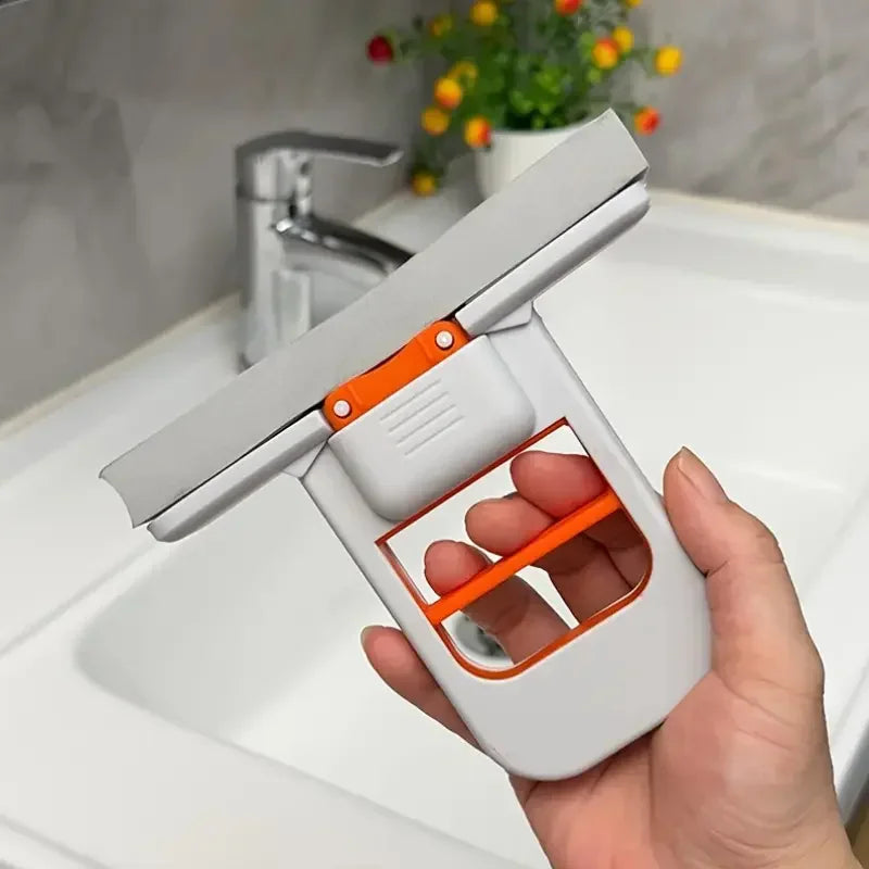 Handheld mini mop with grey sponge and orange accents being held over a sink