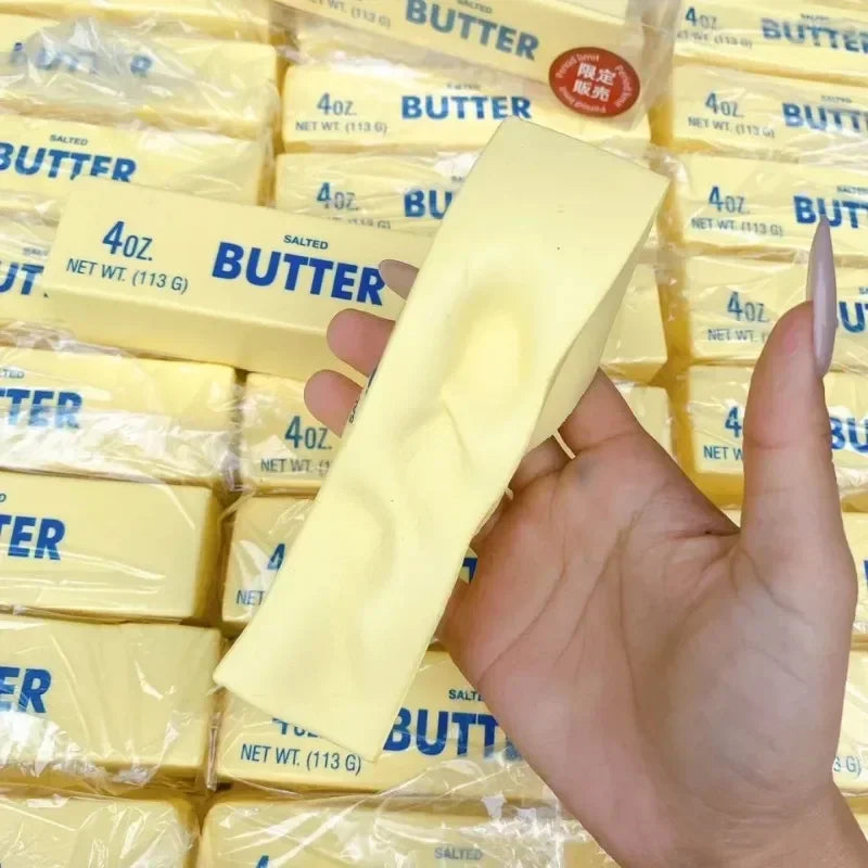 Squishy yellow butter stick fidget toy held in hand with many others in background