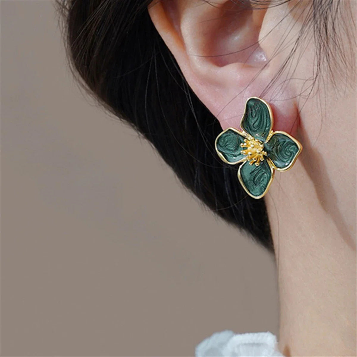 Green floral stud earring worn on earlobe