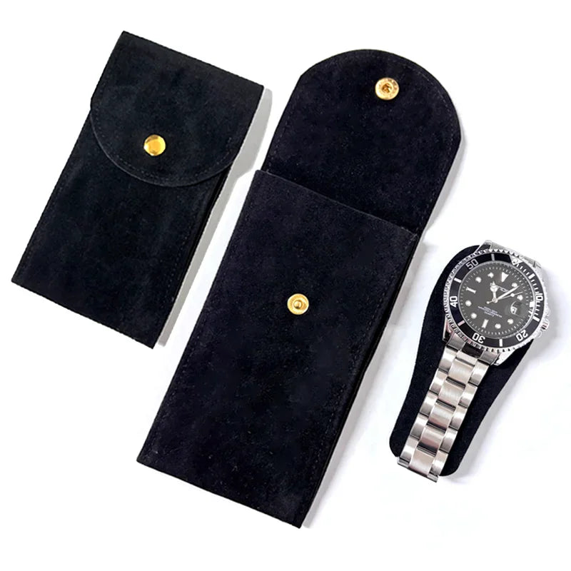 A black suede watch storage pouch with a snap button and a stainless steel wristwatch.