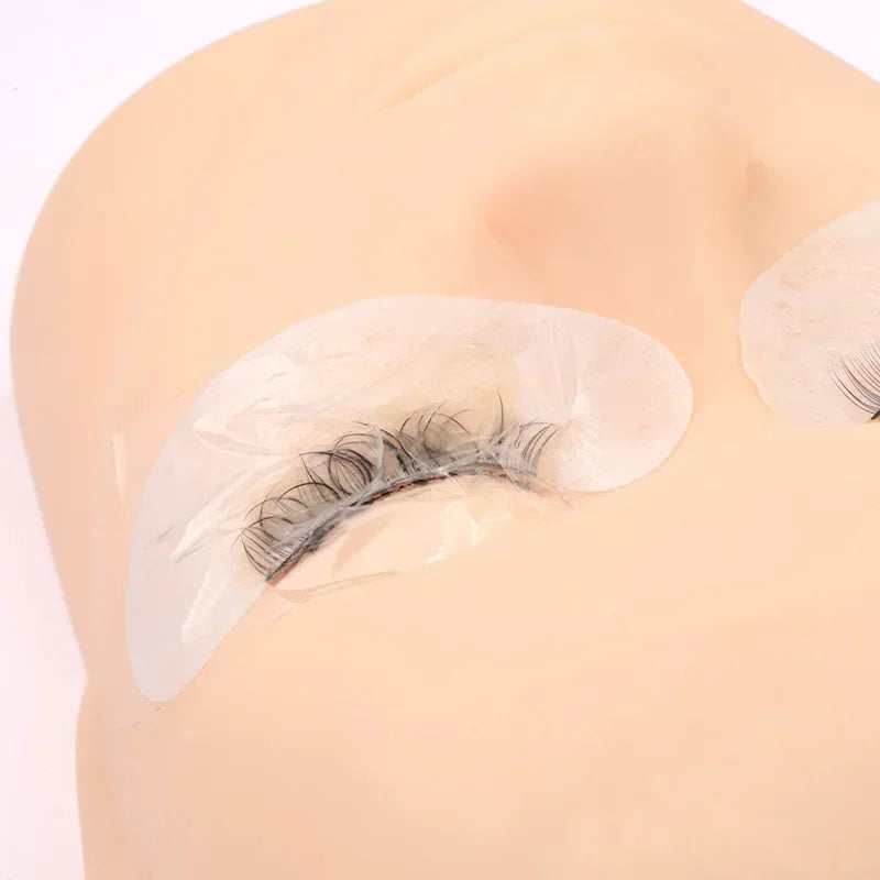 Plastic film wrap applied over an eyebrow tattoo on a practice mannequin head