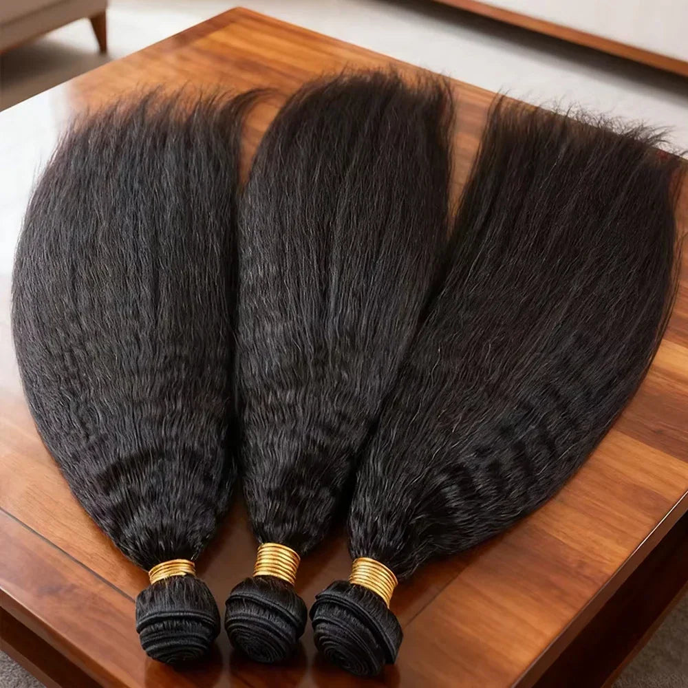 Three bundles of black kinky straight human hair extensions lying on a wooden table