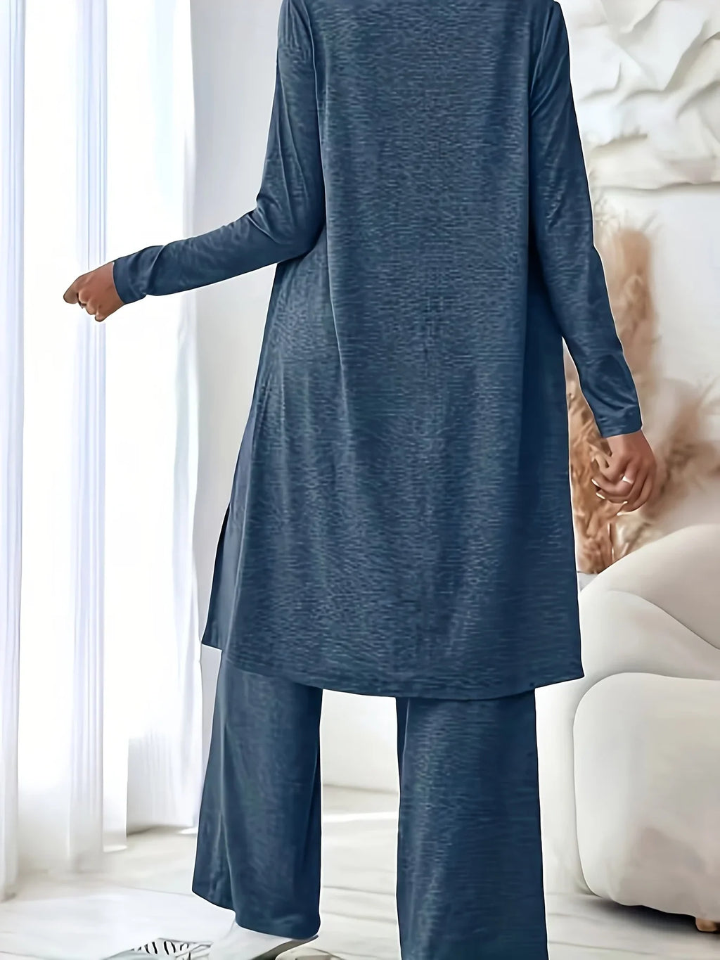 A woman wearing a blue three-piece loungewear set, viewed from the back to show the long cardigan and wide-leg pants