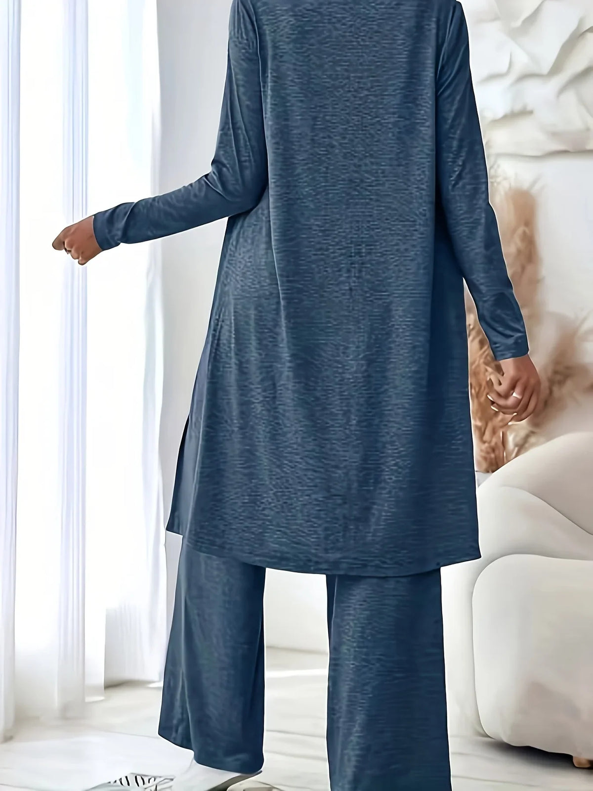A woman wearing a blue three-piece loungewear set, viewed from the back to show the long cardigan and wide-leg pants