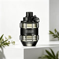 A glass perfume bottle shaped like a grenade, in a transparent black finish with a black band, on a white pedestal with