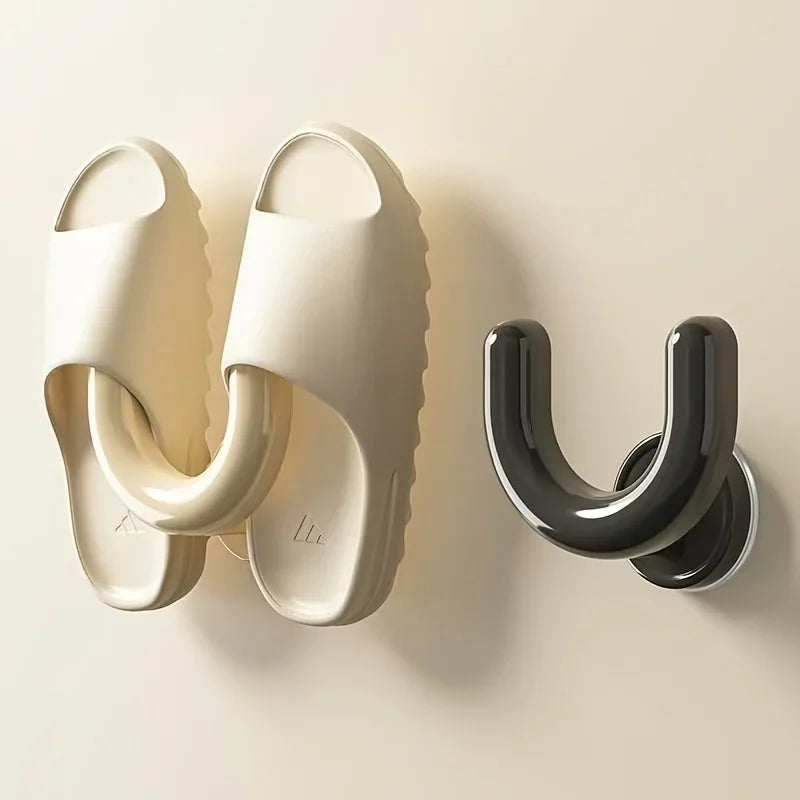 A black and a cream wall-mounted slipper rack holding a pair of cream sandals.