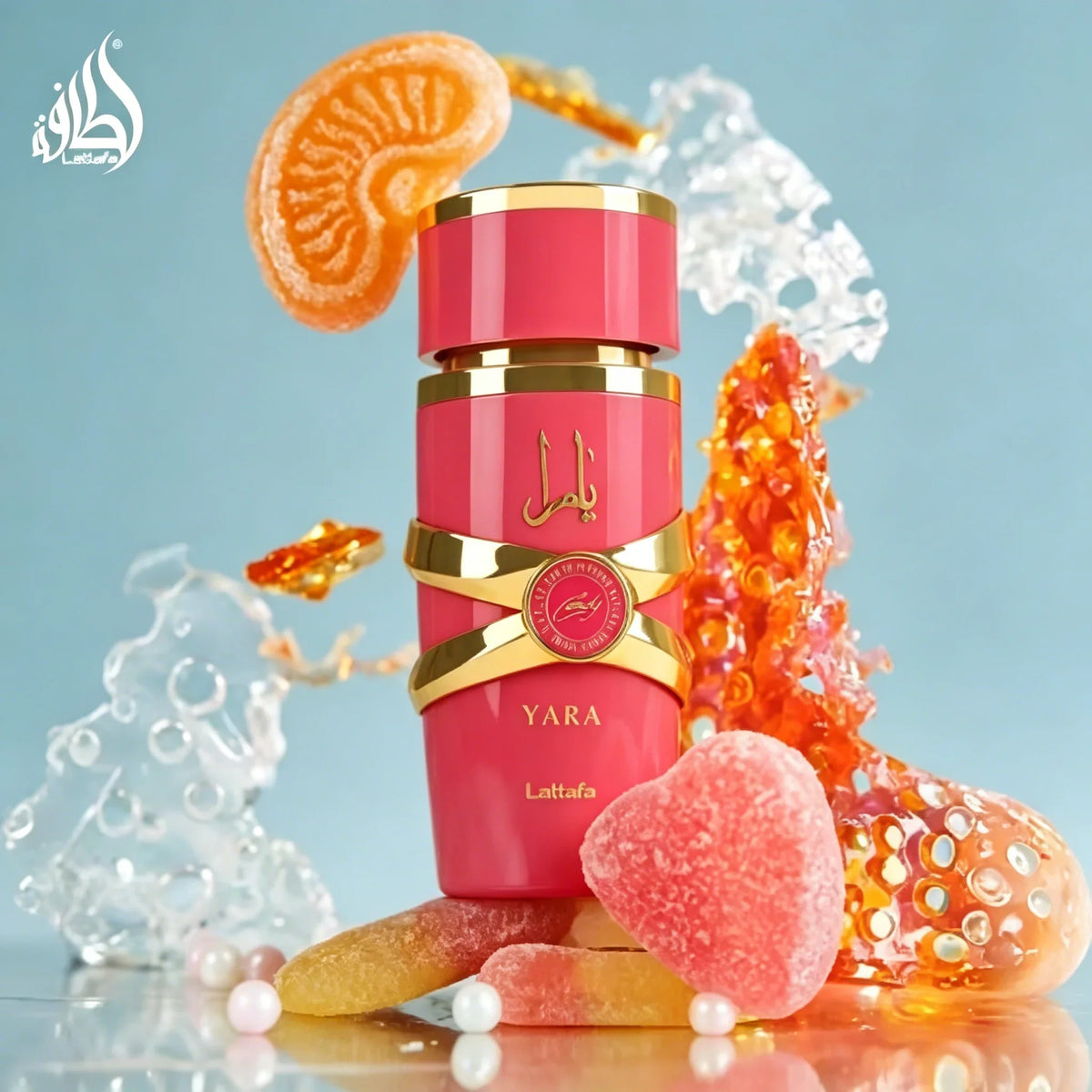 Pink bottle of Yara Candy Eau de Parfum with decorative candy and fruit pieces on a blue background