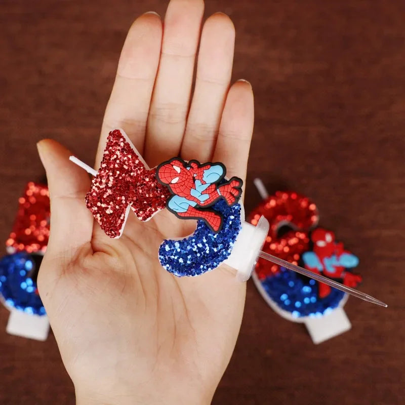 Hand holding glittery number birthday candles with cartoon superhero decoration