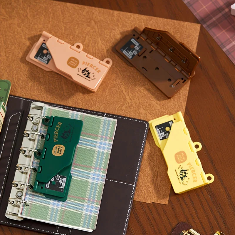 A set of four colorful portable mini hole punchers arranged on a wooden surface.