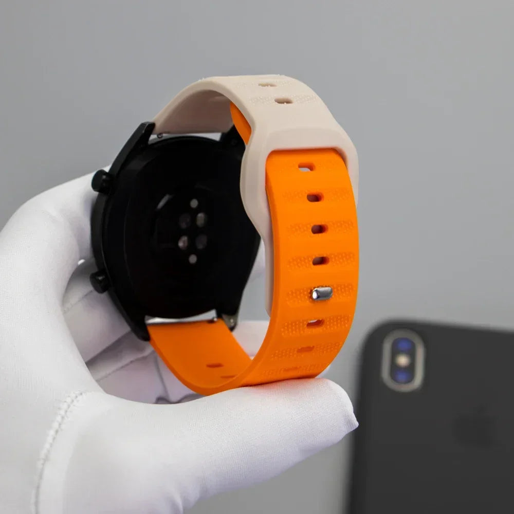 Back view of a black smart watch with an orange and white silicone sports strap held in a gloved hand