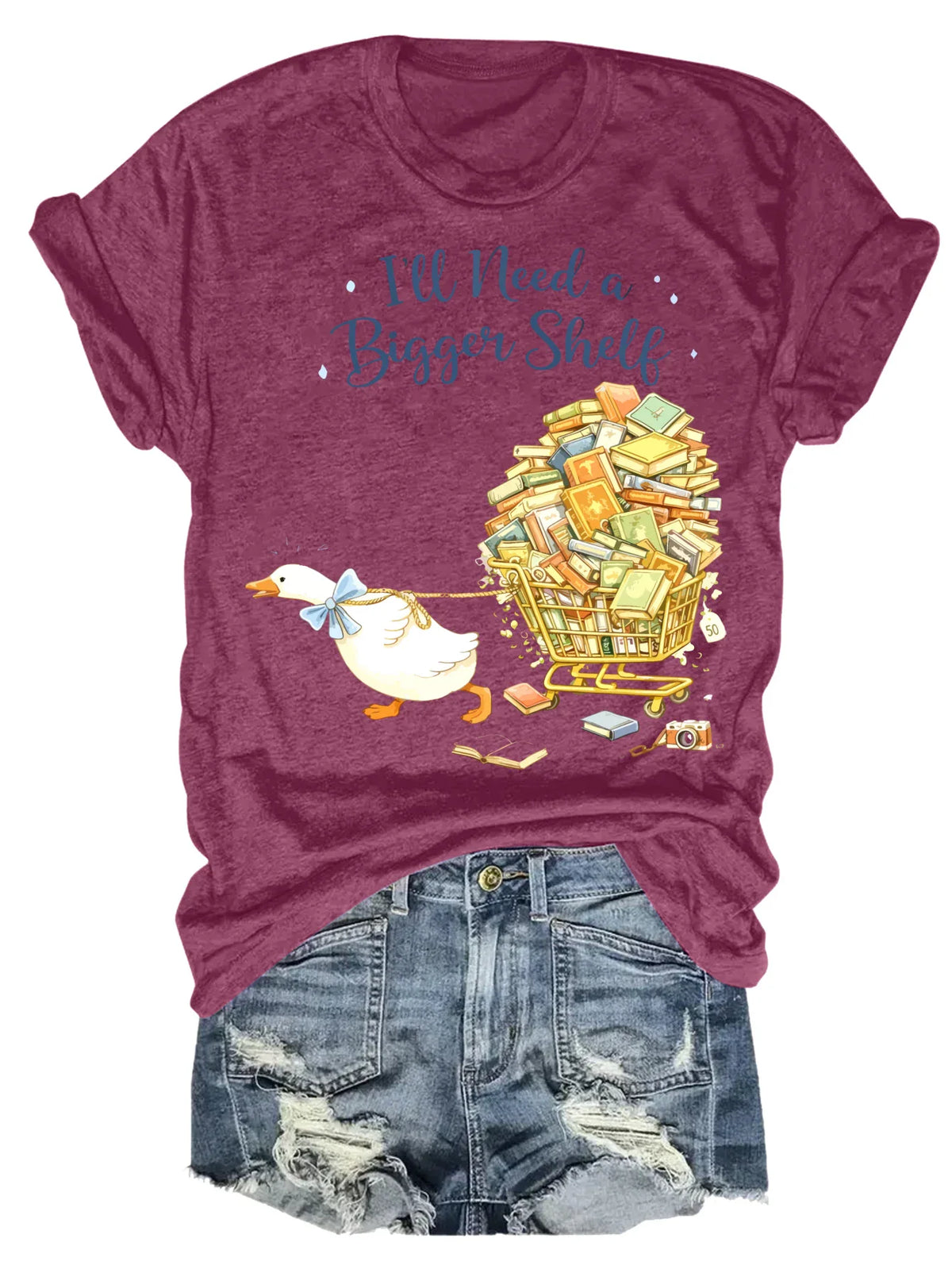 Maroon short-sleeved t-shirt with a duck pulling a book cart graphic print, styled with denim shorts