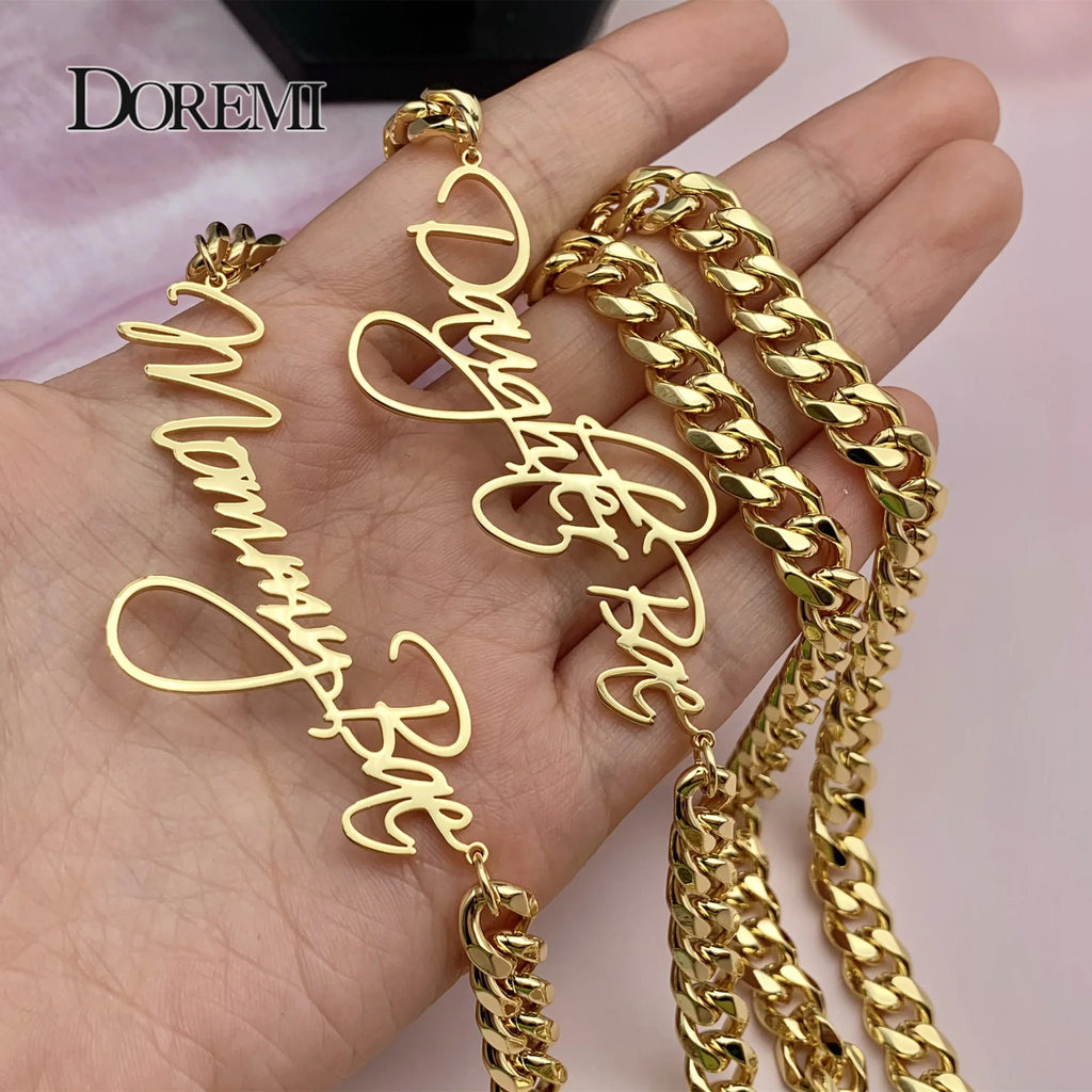 Gold custom nameplate necklaces held in a hand