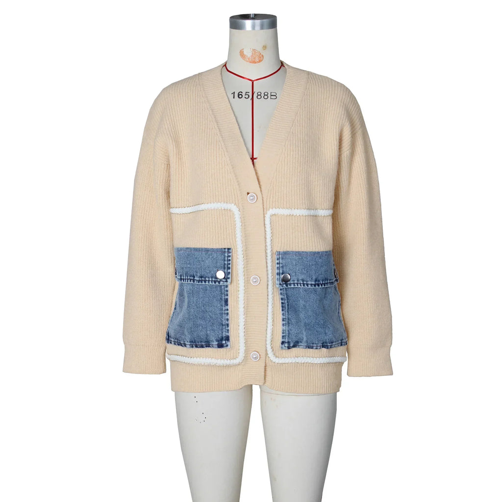 Front view of a beige knit cardigan with blue denim pockets and white stitching on a mannequin.
