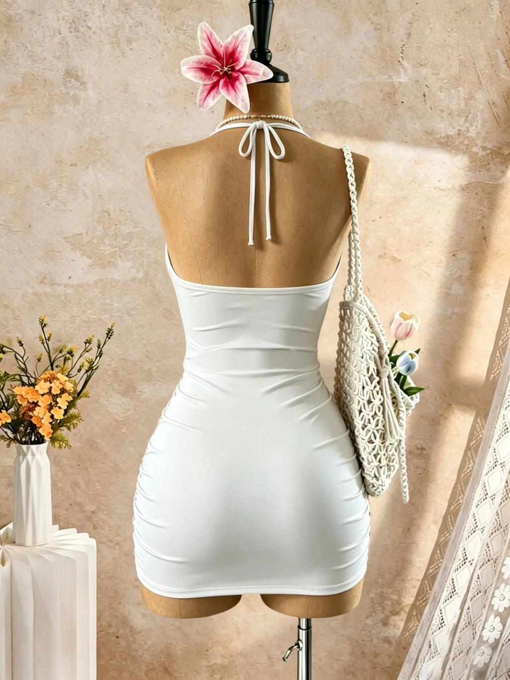 Back view of a white halter neck mini dress with ruched design on a mannequin