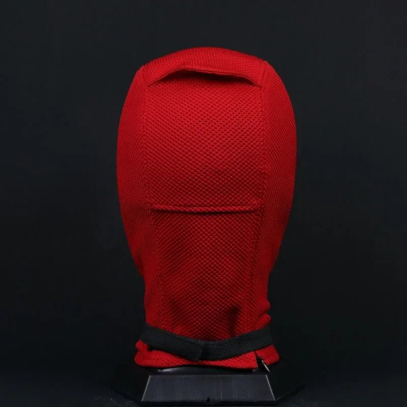 Back view of a red and black knitted superhero mask on a black display stand
