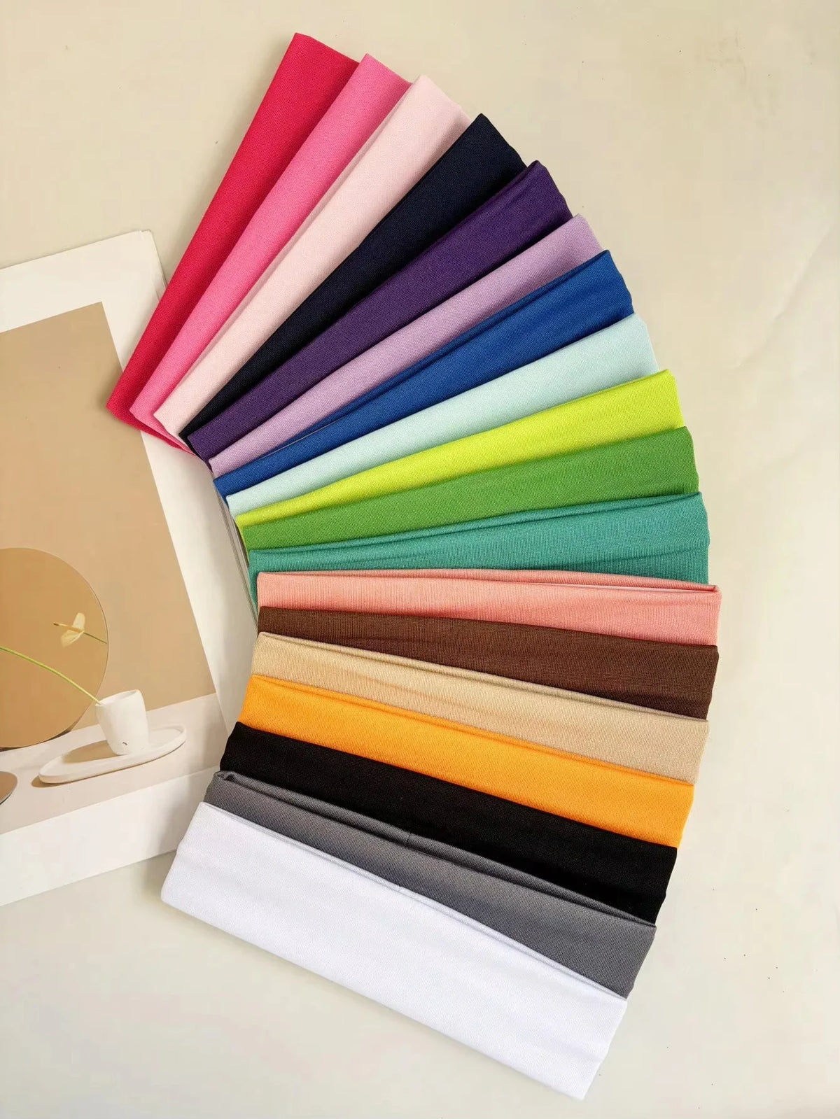 A fanned-out collection of various solid-colored fabric headbands on a plain background.