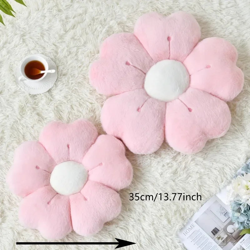 Two pink plush flower pillows on a fluffy white rug with a small cup of tea.