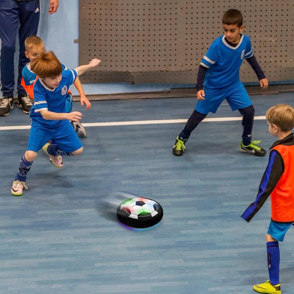 Children playing indoor soccer with a hovering LED air power ball