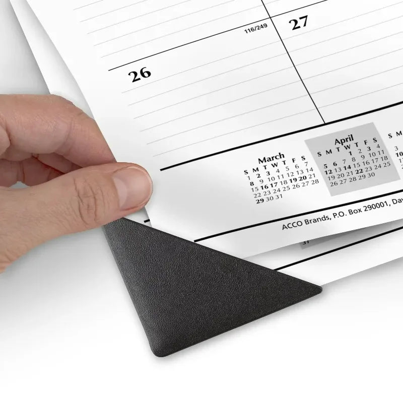 Hand lifting the corner of a desk pad calendar to show the corner protector detail