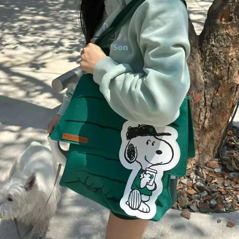 Person carrying a green shoulder tote bag featuring a Snoopy character design