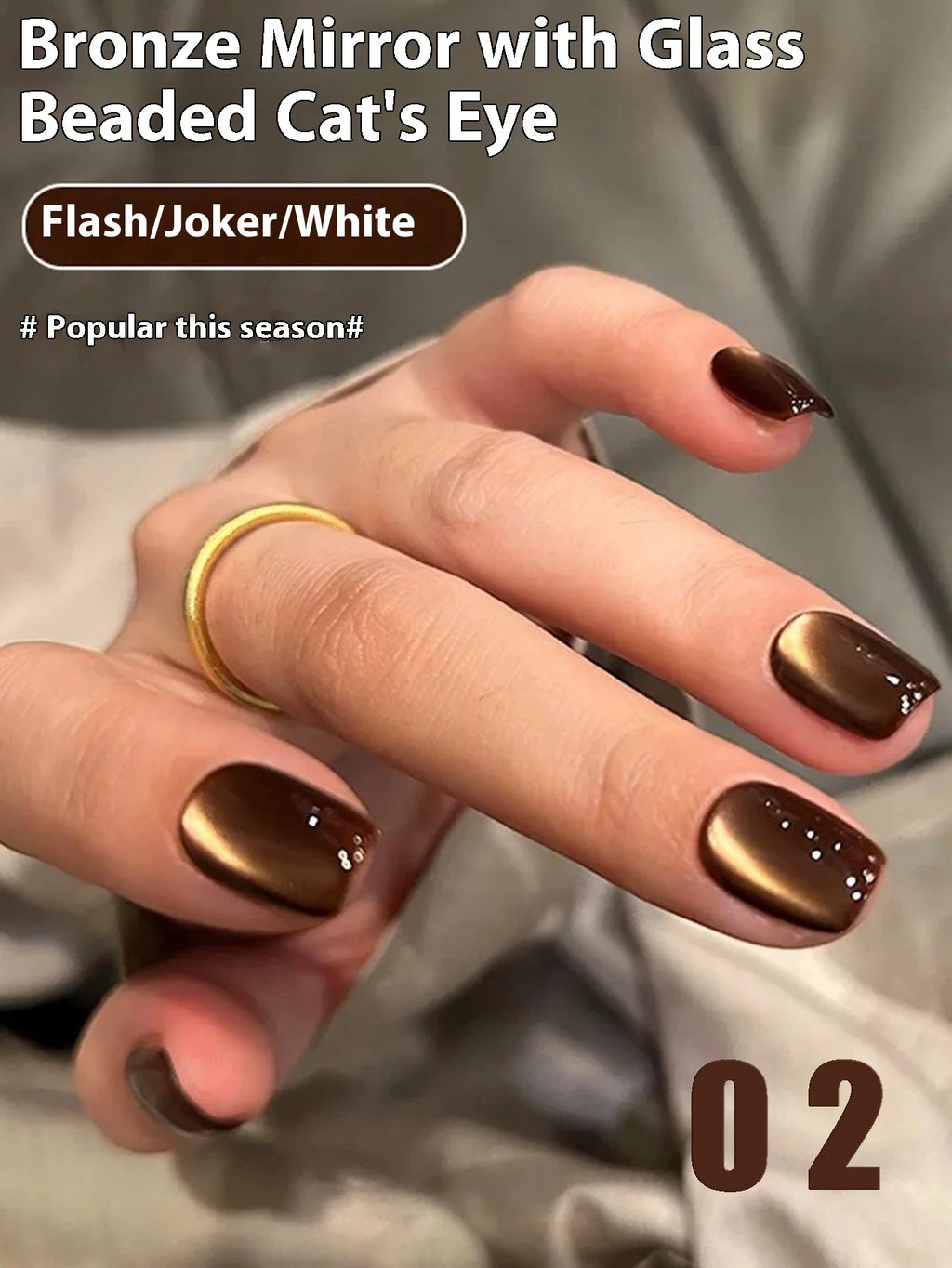 A woman's hand with brown cat eye gel nails, featuring a gold ring.