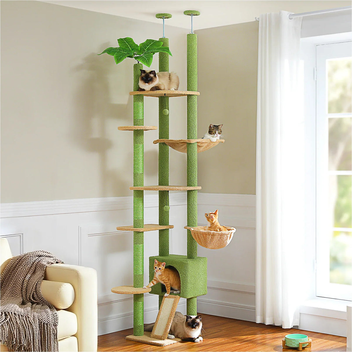 Tall floor-to-ceiling multi-level cat tree with green platforms and sisal scratching posts in a cozy living room.