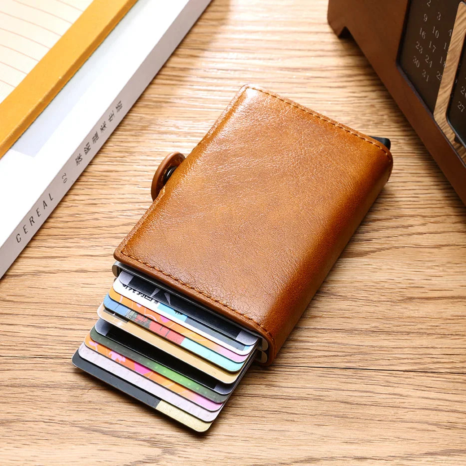 Brown slim leather wallet with multiple credit cards partially ejected on a desk surface.