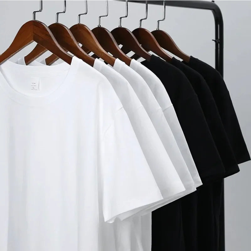 Collection of plain white and black cotton t-shirts hanging on clothes hangers