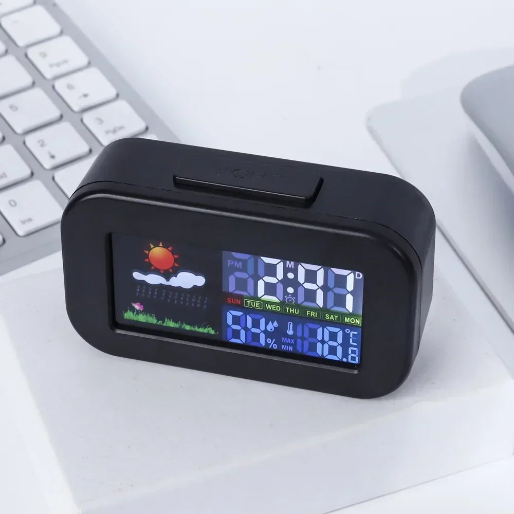 Black digital weather station clock showing colorful display, humidity, and temperature
