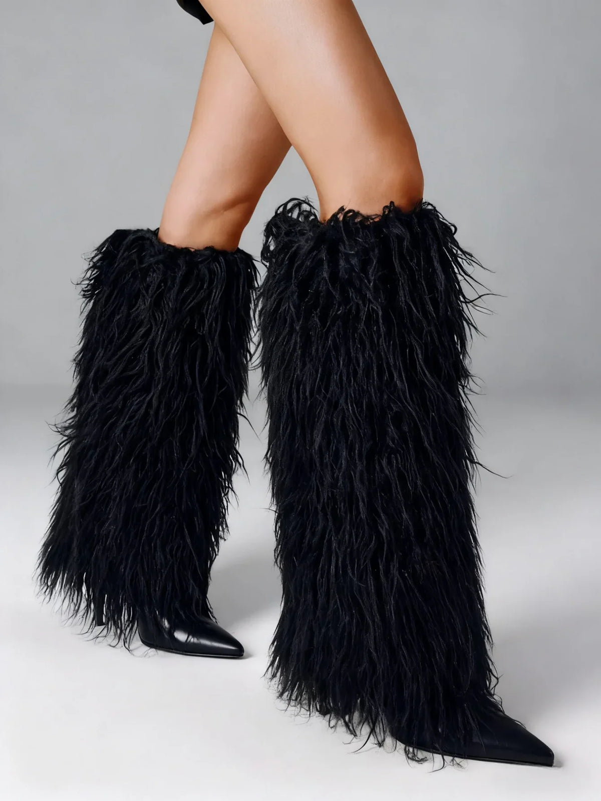 Black faux fur knee high stiletto boots with a pointed toe
