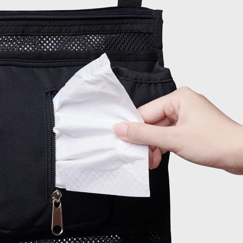Close-up of a hand pulling tissues from a pocket on a black stroller organizer bag
